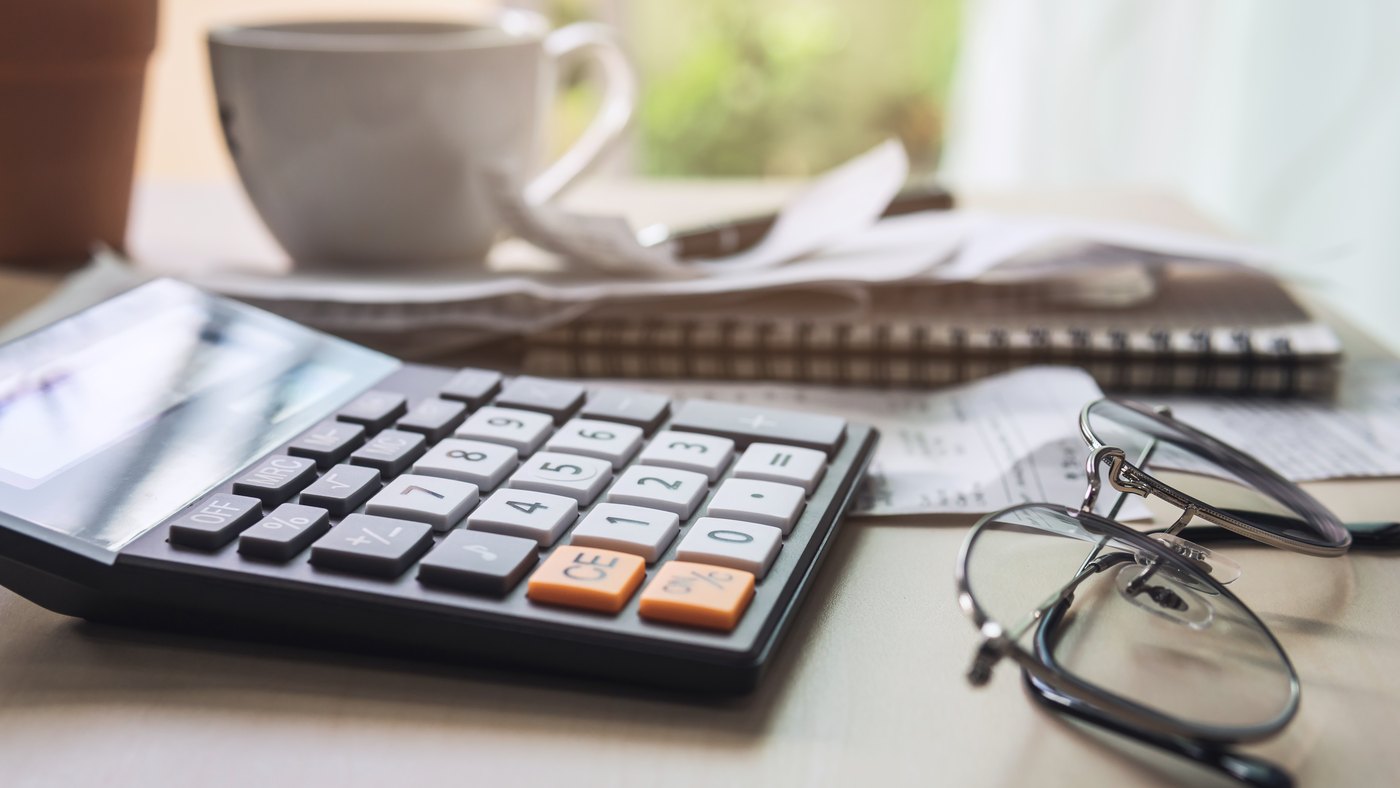 Calculadora, recibos y lentes sobre el escritorio para revisar gastos médicos deducibles