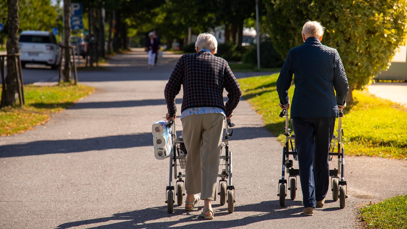 Pareja de adultos mayores caminando con andaderas con ruedas al atardecer en un parque